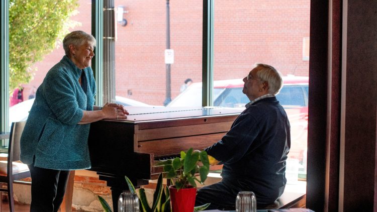 Man playing to a woman who is leaning on the piano