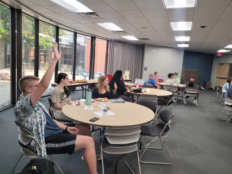 Youth Advisory Council students voting with a young man in front raising his hand