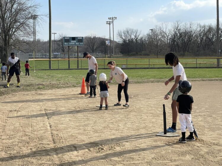 Young people teaching toddlers t-ball