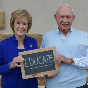 Older couple holding sign reading Educate