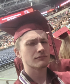 young man in red graduation outfit with cords
